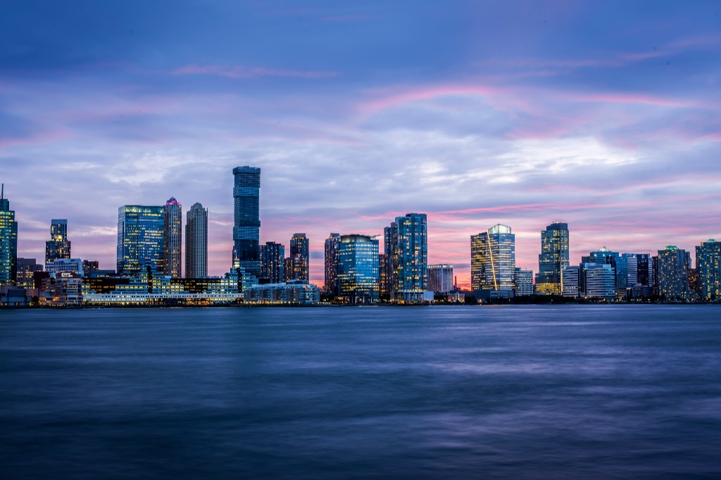 City skyline at dusk with buildings reflected on the water