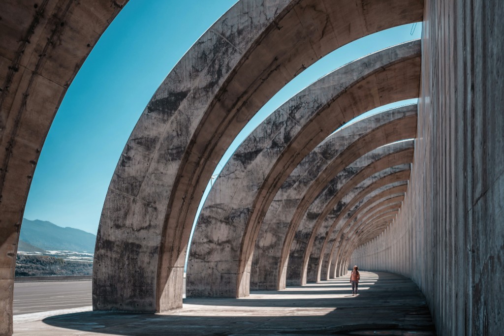 Curved concrete arch structure with a person walking along the walkway