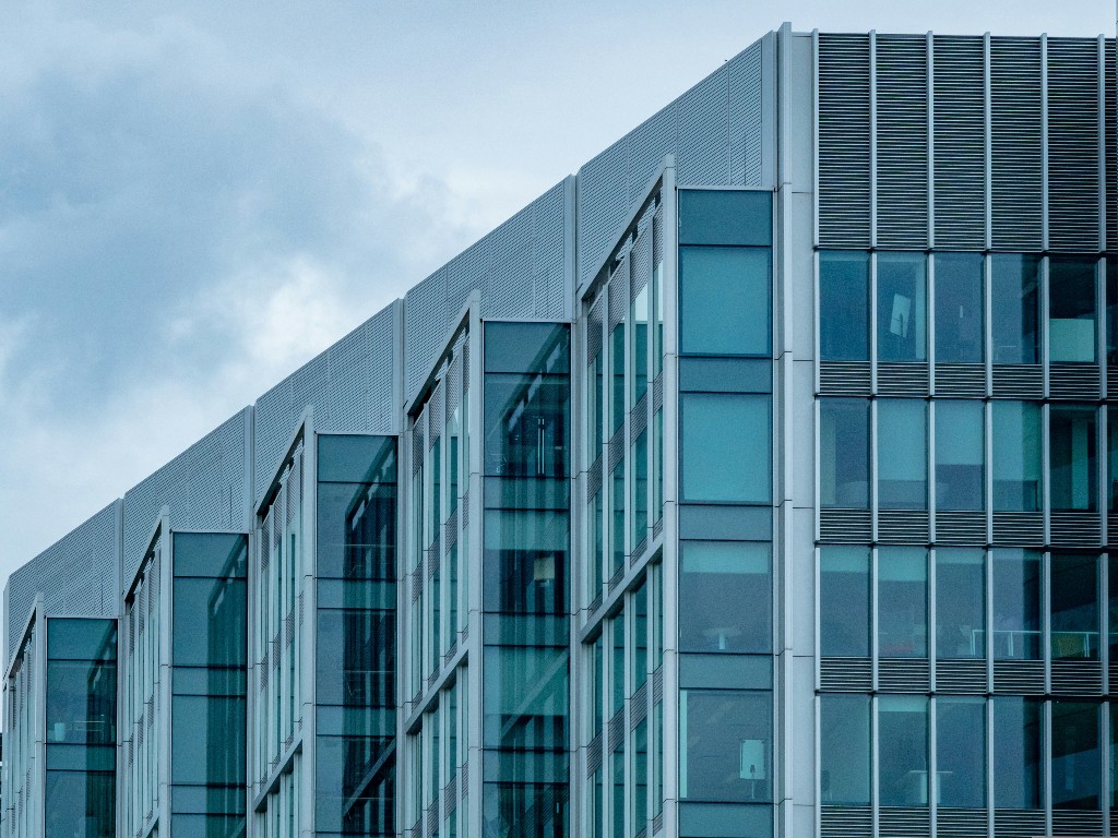 Modern glass office building with teal-tinted windows viewed from below