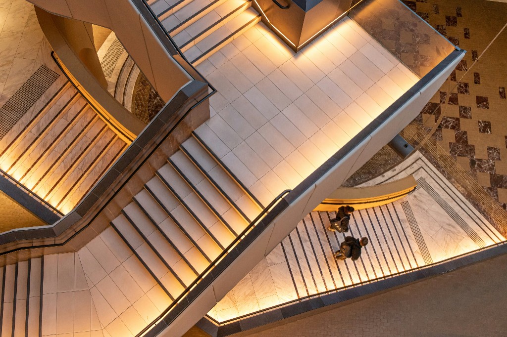 Overhead view of a modern staircase with warm amber lighting and two people walking